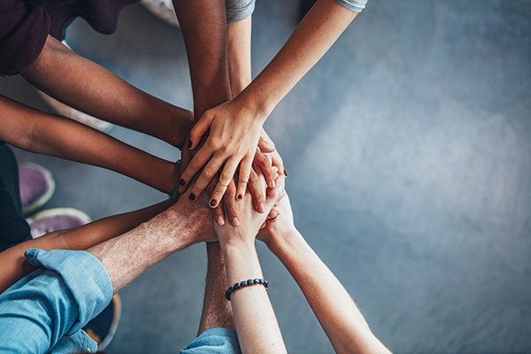 Close up top view of young people putting their hands together. Friends with stack of hands showing unity and teamwork.
