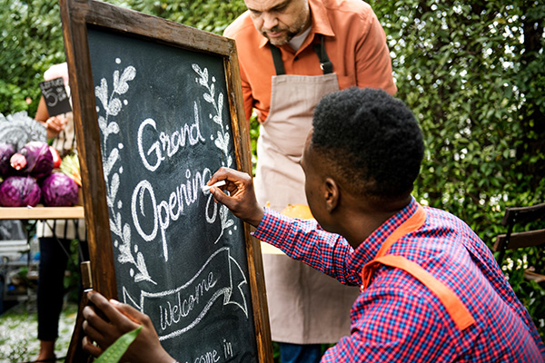 Man writes grnad opening on a chalkboard