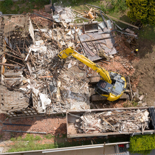 Home being demolished by a crane and putting the pieces into a dump truck