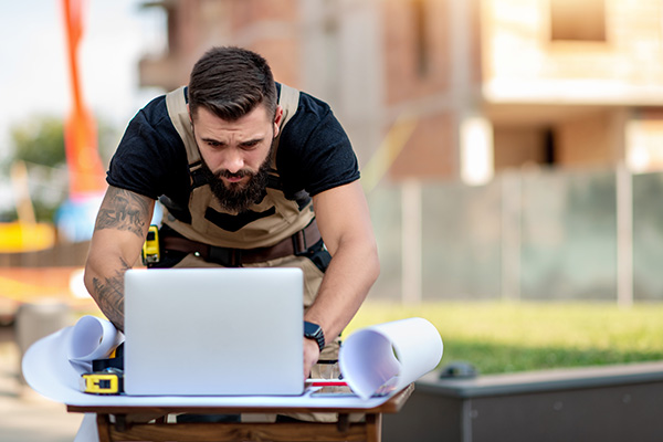 Young engineer using laptop in front of the building.