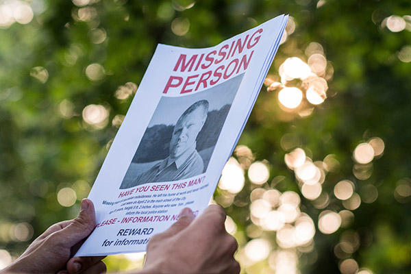 Hands hold a Missing Person flyer.