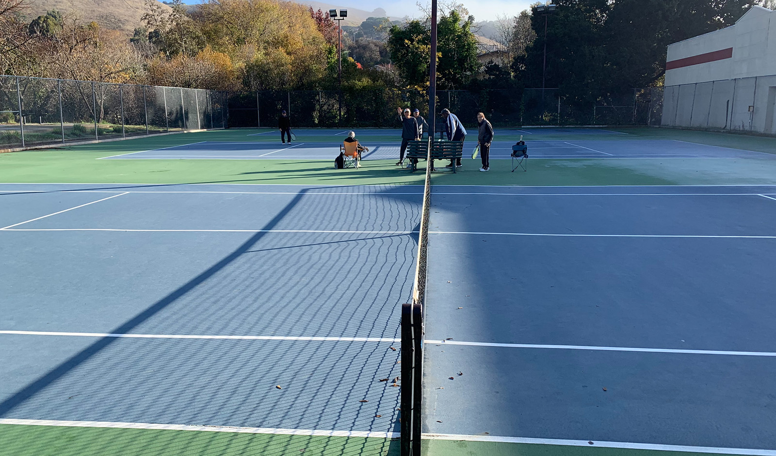 Pople enjoying the tennis court on a sunny day