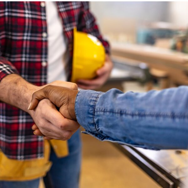 Homeowner shaking the hand of a contractor with a yellow construction hat