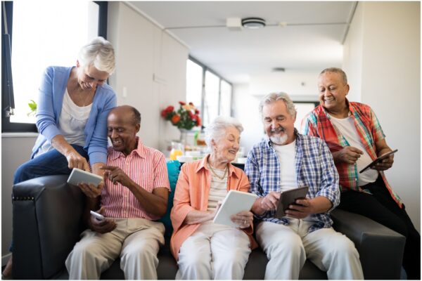 five seniors looking at tablets and smiling