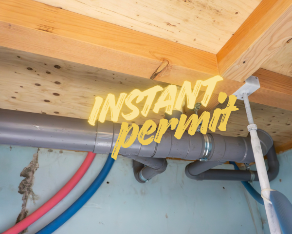 Plumbing pipes installed beneath wooden floor joists, including gray drain pipes and red and blue supply lines, with the words “INSTANT permit” overlaid in yellow text.