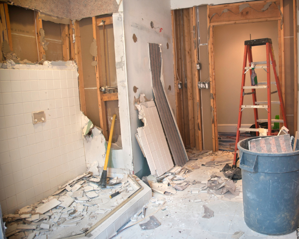 Interior demolition work showing exposed studs, tile removal, and preparation for residential remodeling.